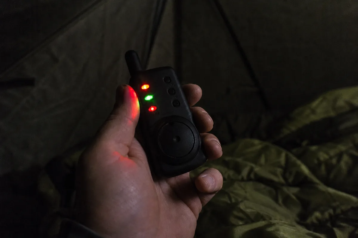 Récepteur de détecteurs tenu dans la main sous un bivvy en pêche de nuit